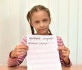 The girl shows a leaf of a calligraphical copy-book with words. The Russian text - copy-books, an ostrich Royalty Free Stock Photo