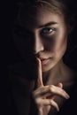 Girl shows a sign of silence. Face on a dark background. Dont Talk Concept Royalty Free Stock Photo