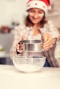 Girl sifts flour for tasty cookies for christmas