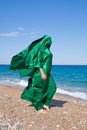 Girl silhouette in green tissue on the sea beach