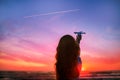 Girl silhouette holding airplane model in her hand in front of scenic sunset sky background. air transportation concept. Royalty Free Stock Photo