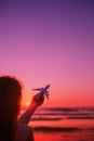 Girl silhouette holding airplane model in her hand in front of scenic sunset sky background. air transportation concept. Royalty Free Stock Photo