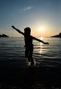 Girl silhouette and sea. Cheerful little child girl jumping and hovering in the air on the background of sunset sky and Adriatic s Royalty Free Stock Photo