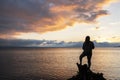 A girl silhouette stands on the shore of the lake looks at beautiful sunset.