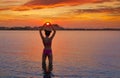 Girl silhouette at sunset heart shape hands Royalty Free Stock Photo