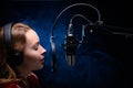 Girl singer sings into a microphone, with a spectacular background, vocals, recording studio, recording a track. On a black Royalty Free Stock Photo