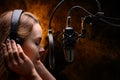Girl singer sings into a microphone, with a spectacular background, vocals, recording studio, recording a track Royalty Free Stock Photo