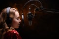 Girl singer sings into a microphone, with a spectacular background, vocals, recording studio, recording a track Royalty Free Stock Photo