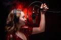 Girl singer sings into a microphone, with a spectacular background, vocals, recording studio, recording a track Royalty Free Stock Photo