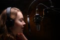 Girl singer sings into a microphone, with a spectacular background, vocals, recording studio, recording a track Royalty Free Stock Photo