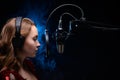 A girl singer sings into a microphone, with a spectacular background, vocals, a recording studio, recording a track. On a black Royalty Free Stock Photo