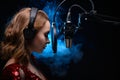 A girl singer sings into a microphone, with a spectacular background, vocals, a recording studio, recording a track. On a black Royalty Free Stock Photo