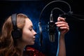 A girl singer sings into a microphone, with a spectacular background, vocals, a recording studio, recording a track. On a black Royalty Free Stock Photo