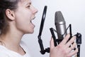 The girl is singing into the studio microphone. Recording the vocals of a young singer.