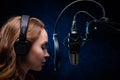 Girl singer sings into a microphone, with a spectacular background, vocals, recording studio, recording a track. On a black Royalty Free Stock Photo