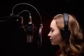 Girl sings in a red dress and red backlight. Microphone in a recording studio. Effective background. Vocal. Vocal schools and Royalty Free Stock Photo