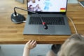 Girl sit on chair and play in online game with laptop and microphone on table at home.