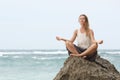 Girl sit at the seaside on the rock and meditating in yoga woman pose Royalty Free Stock Photo