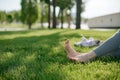 The girl sit on yoga mat outdoor. Feet on a background of green grass