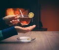 Girl siting near the fireplace with a cup of tea with lemon. co Royalty Free Stock Photo