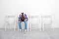 The girl siting on a white chair with his head down. She is somewhat upset and emotionally upset