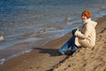 Girl sits on beach, an autumn sunny day