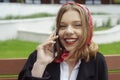 A girl sits on a bench in the street and speaks on the phone, orders a taxi by phone. Girl holds mobile in hands and laughs,