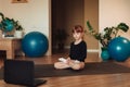 the girl sits on a black mat. the girl watches the new exercises on her laptop