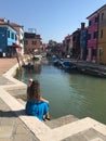 Girl sits on a canal in Burano