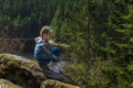 A girl sits on a cliff and looks at nature, girl sitting on a rock and enjoying valley view.