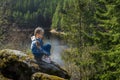 A girl sits on a cliff and looks at nature, girl sitting on a rock and enjoying valley view.