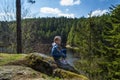 A girl sits on a cliff and looks at nature, girl sitting on a rock and enjoying valley view.