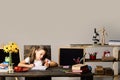 Girl sits at desk with books, flowers, fruit and blackboard Royalty Free Stock Photo