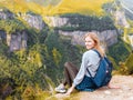 A girl sits on the edge of the cliff and looking at the valley. Woman enjoying the forest view from the top of the Royalty Free Stock Photo