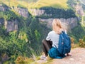 A girl sits on the edge of the cliff and looking at the valley. Woman enjoying the forest view from the top of the Royalty Free Stock Photo