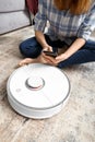 The girl sits on the floor and controls the robot vacuum cleaner using a smartphone, smart home Royalty Free Stock Photo