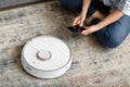 The girl sits on the floor and controls the robot vacuum cleaner using a smartphone, smart home Royalty Free Stock Photo