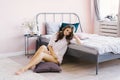 Girl sits on the floor next to the bed, a young woman woke up, a portrait of a brunette in pink pajamas Royalty Free Stock Photo