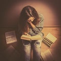 A girl sits on the floor and reading a book straightens hair with her hand close up retro toning