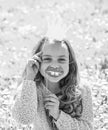 Girl sits on grass at grassplot, green background. Child posing with cardboard smiling lips and crown for photo session