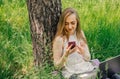 girl sits on the grass and works at a laptop. looks at the phone. freelance. selfeducation. the concept of remote Royalty Free Stock Photo