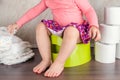 The girl sits on a green pot and learns elementary hygiene, switching from diapers to a toilet Royalty Free Stock Photo