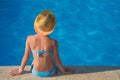 The girl sits with her back to the camera at the edge of the pool. The blue swimsuit matches the color of the pool water Royalty Free Stock Photo
