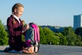 The girl sits on her knees and takes out the textbooks from her backpack