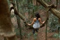 The girl sits on a huge liana tree branch in the jungle