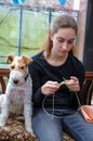 Girl sits and knits, her dog keeps her company