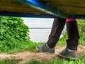 The girl sits by the lake, wears on her feet sneakers. Female legs Royalty Free Stock Photo