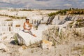 The girl sits on a large piece of marble , view of marble quarry