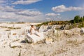 The girl sits on a large piece of marble, view of marble quarry