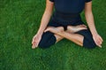 The girl sits in a lotus position on the green grass and does yoga